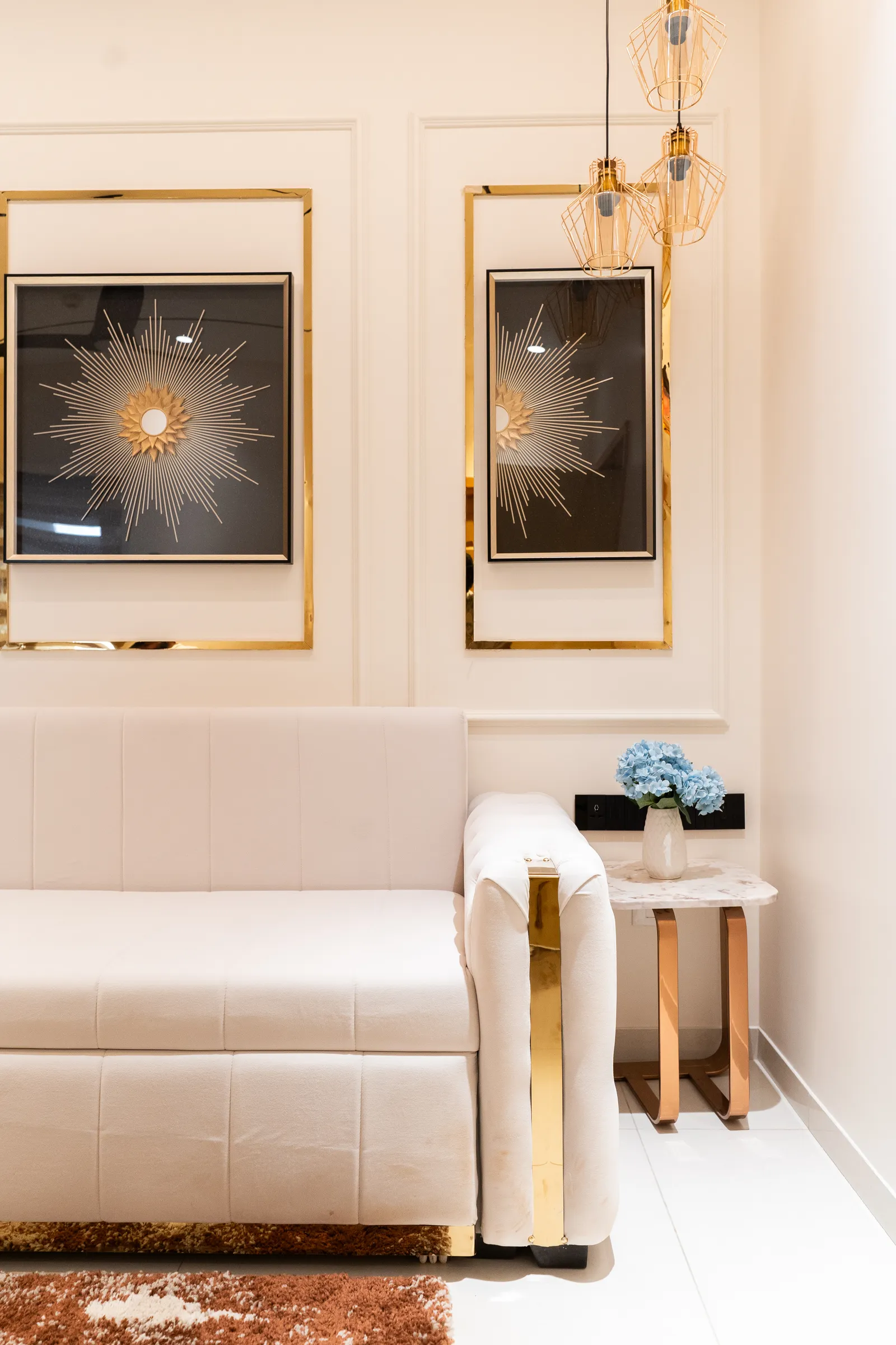 Cream sofa with gold-framed starburst artworks — Abhishek's Residence
